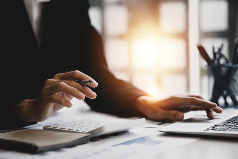 Hands of woman in business suit on desk using calculator 